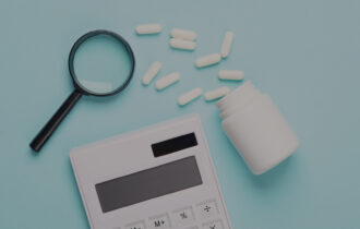 A magnifying glass, a bottle of pills and a calculator on a light blue background