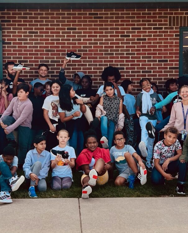 Kids in front of a brick building holding up new sneakers