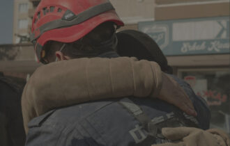 A rescue man with an orange hardhat hugging someone in need of help