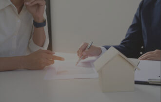 Two people whose faces are cutoff from frame sitting at a table going over business plans