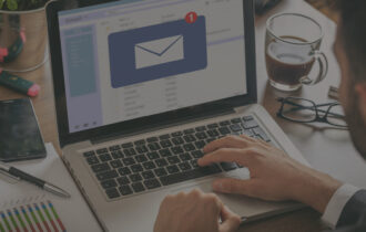 A computer with a man in a suit typing on it that has an email notification on the screen