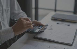 Someone sitting at a table using a calculator with data information on the table